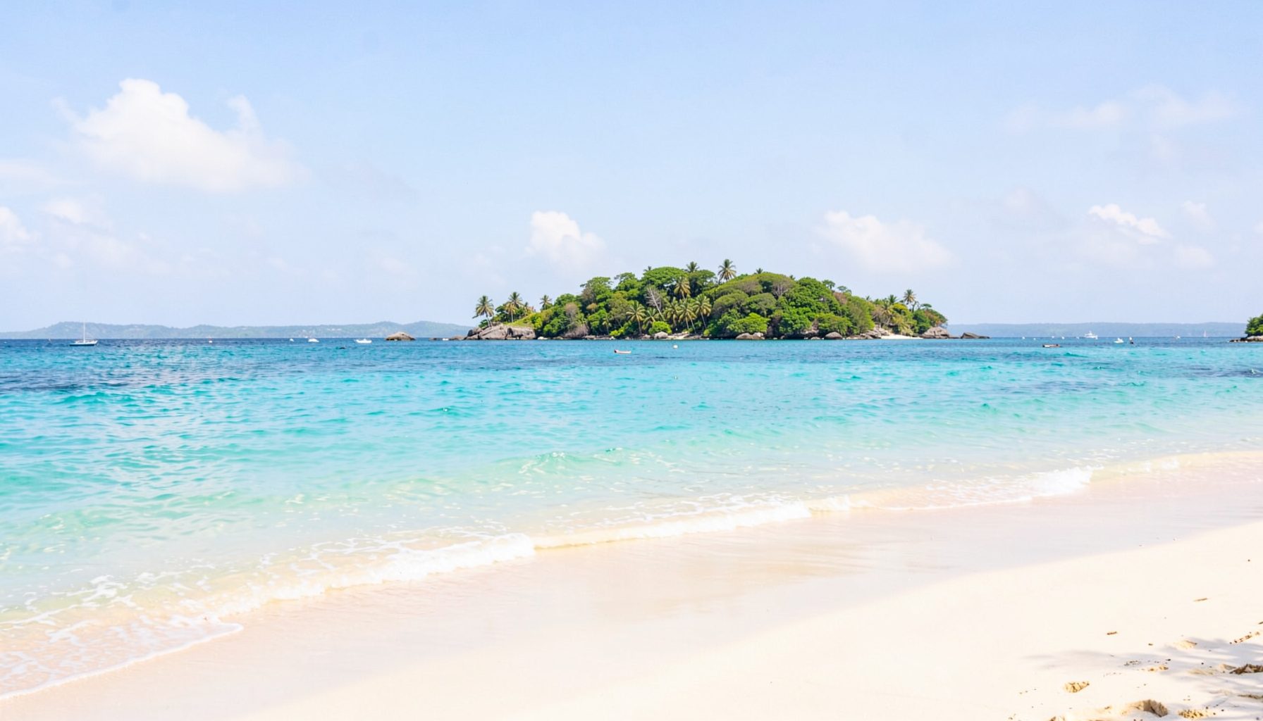 Warm tropical coastline with turquoise water and soft sandy beach under a bright sky, calm island atmosphere